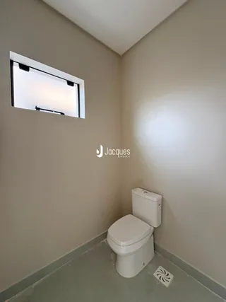 Foto de um banheiro interno com vaso sanitário e parede clara.