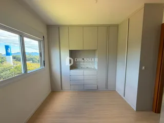Interior de um cômodo com armários embutidos e janela de vista para a paisagem.