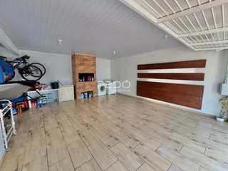 Interior de uma sala ampla com piso de cerâmica e painéis de madeira.