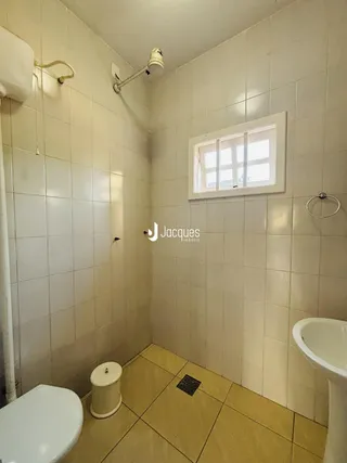 Um banheiro com piso de cerâmica e paredes revestidas de azulejos brancos.