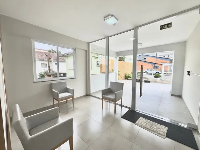 Sala de estar com dois assentos e portas de vidro que dão acesso ao exterior.