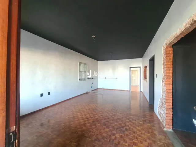 Interior de um ambiente longo com piso de cerâmica marrom e teto escuro.