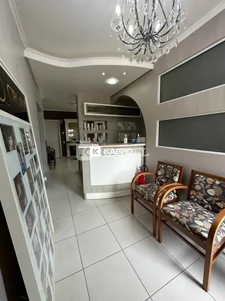 Ambiente interno com teto decorado por lustre de cristal e piso de cerâmica.