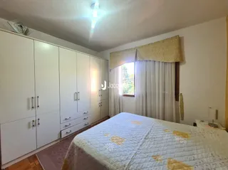 Quarto com cama e cortinas brancas na sala.