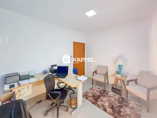 Um escritório com mesa de trabalho e assentos em um ambiente claro.
