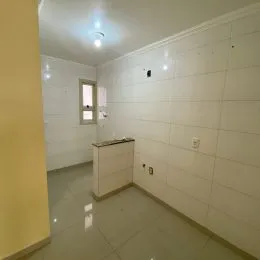 Corredor interno com paredes brancas e piso claro.