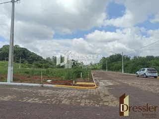 Vista externa de uma propriedade com área pavimentada e vegetação.