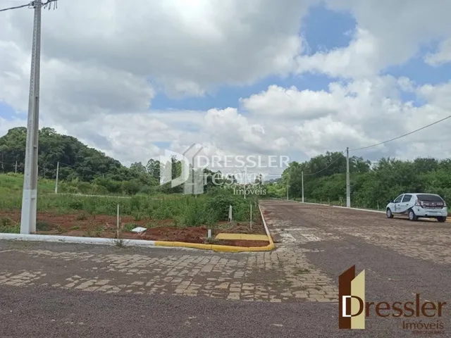 Vista externa de uma propriedade com área pavimentada e vegetação.