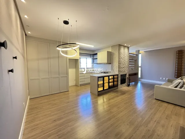 Ambiente de sala de estar e cozinha com piso de madeira clara.