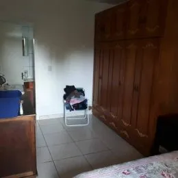 Quarto com armário de madeira e piso de cerâmica.