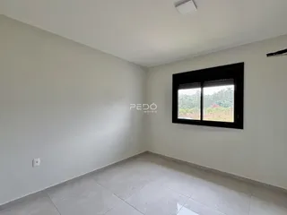 Ambiente interno de uma sala com piso de cerâmica e janela grande.