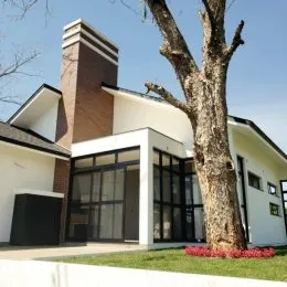 Fachada externa de uma residência em Lajeado, Brasil, com vegetação no primeiro plano.