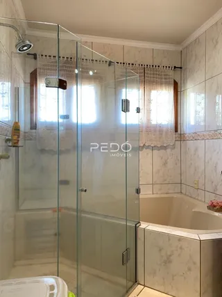 Banheiro com box de vidro e banheira em um imóvel.