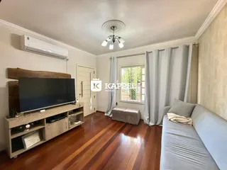 Sala de estar com sofá e televisão em ambiente bem iluminado.