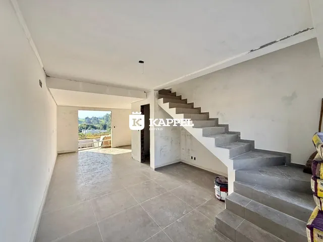 Hall de entrada com escadaria e vista para a paisagem externa.