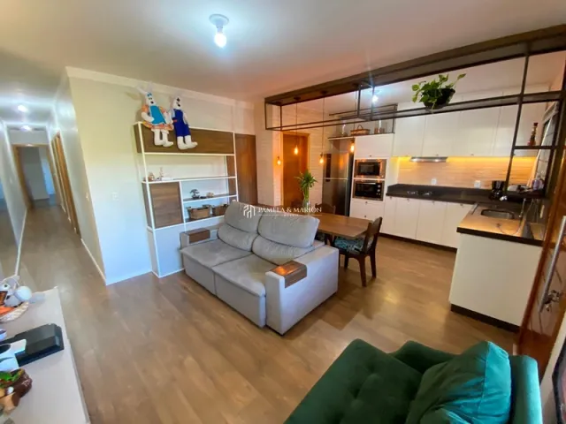Sala de estar com sofá e armários na cozinha ao fundo.