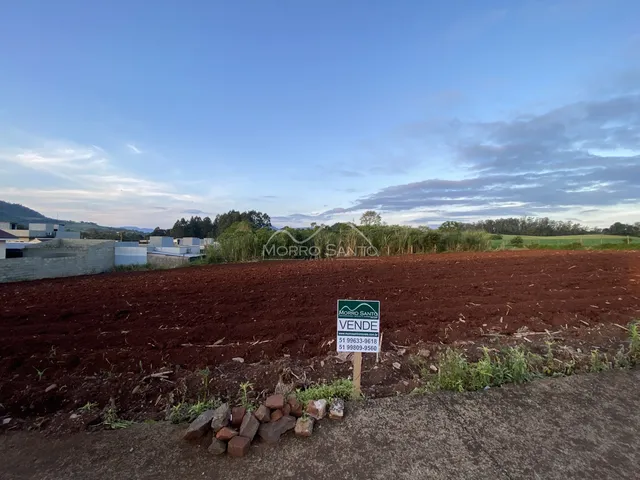 Foto de um campo aberto com terra vermelha sob um céu azul.