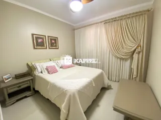 Quarto com cama de casal e cortinas brancas.