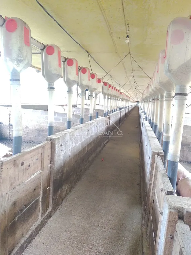 Corredor longo com tubulações visíveis em uma estrutura de concreto.