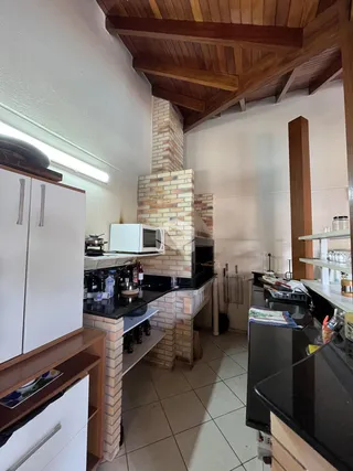 Imagem de uma cozinha com detalhes em tijolo e vigas de madeira.