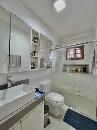 Banheiro moderno com revestimento de azulejos e box de vidro.