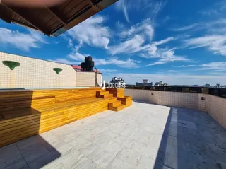 Vista de uma área externa com piso de cerâmica e deck de madeira.