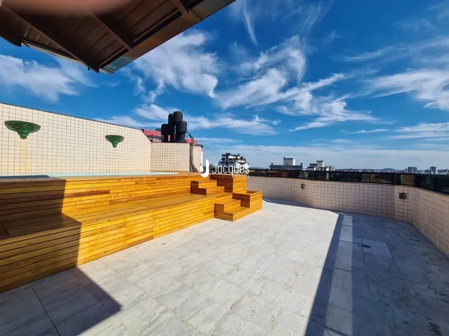 Vista de uma área externa com piso de cerâmica e deck de madeira.