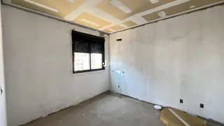 Ambiente interno de uma sala com paredes brancas e piso de concreto cru.