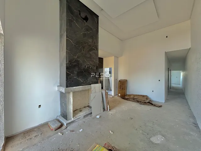 Interior de uma área em construção com parede de pedra exposta.