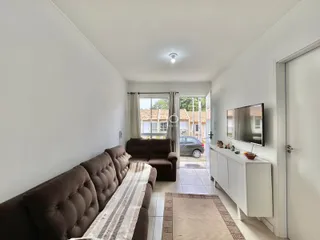 Sala de estar com sofá marrom e piso de cerâmica.