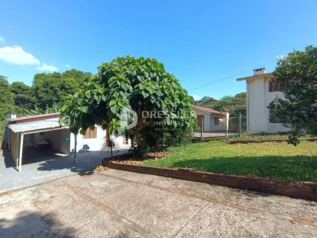 Vista externa de uma residência com jardim e árvores.