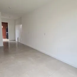 Interior de um ambiente amplo com piso claro e paredes brancas.