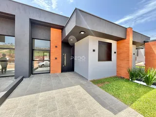 Fachada moderna de uma residência com detalhes em tijolo aparente e piso externo.
