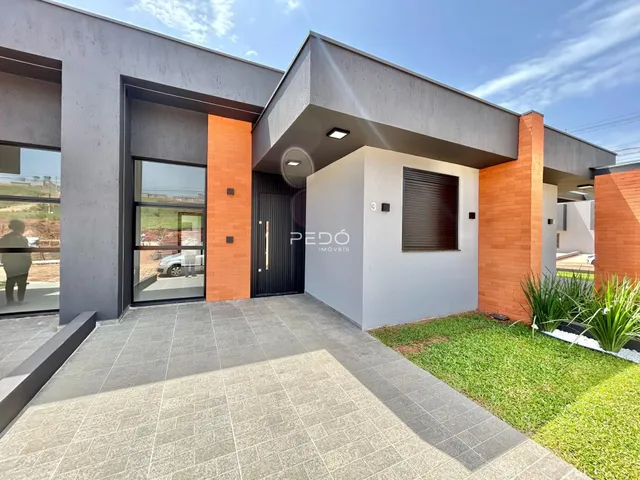 Fachada moderna de uma residência com detalhes em tijolo aparente e piso externo.