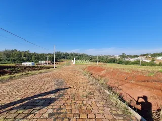 Vista da propriedade com área pavimentada e campo aberto.
