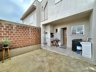 Fachada de uma residência com parede de tijolos aparentes e piso de concreto.