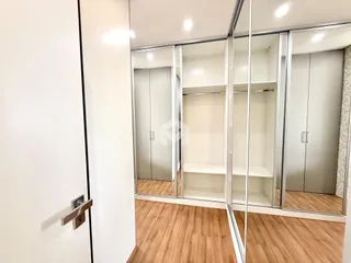 Vista de um corredor interno com portas e espelhos em um imóvel.