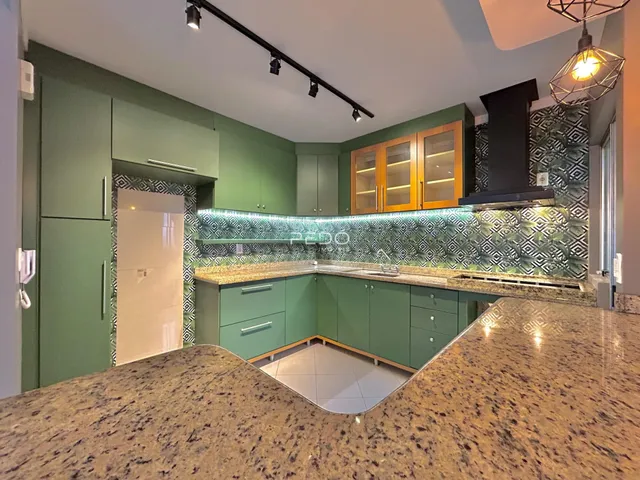Cozinha moderna com armários verdes e bancadas de granito.