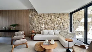 Sala de estar moderna com sofá branco e parede de pedra na residência.