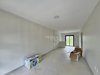 Interior de um corredor longo com paredes brancas e piso claro.
