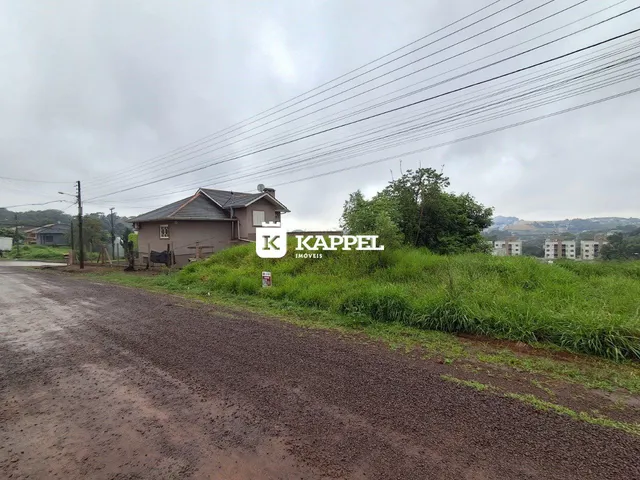 Foto da fachada de uma residência em Lajeado, Brasil, com vegetação e estrada de terra no primeiro plano.