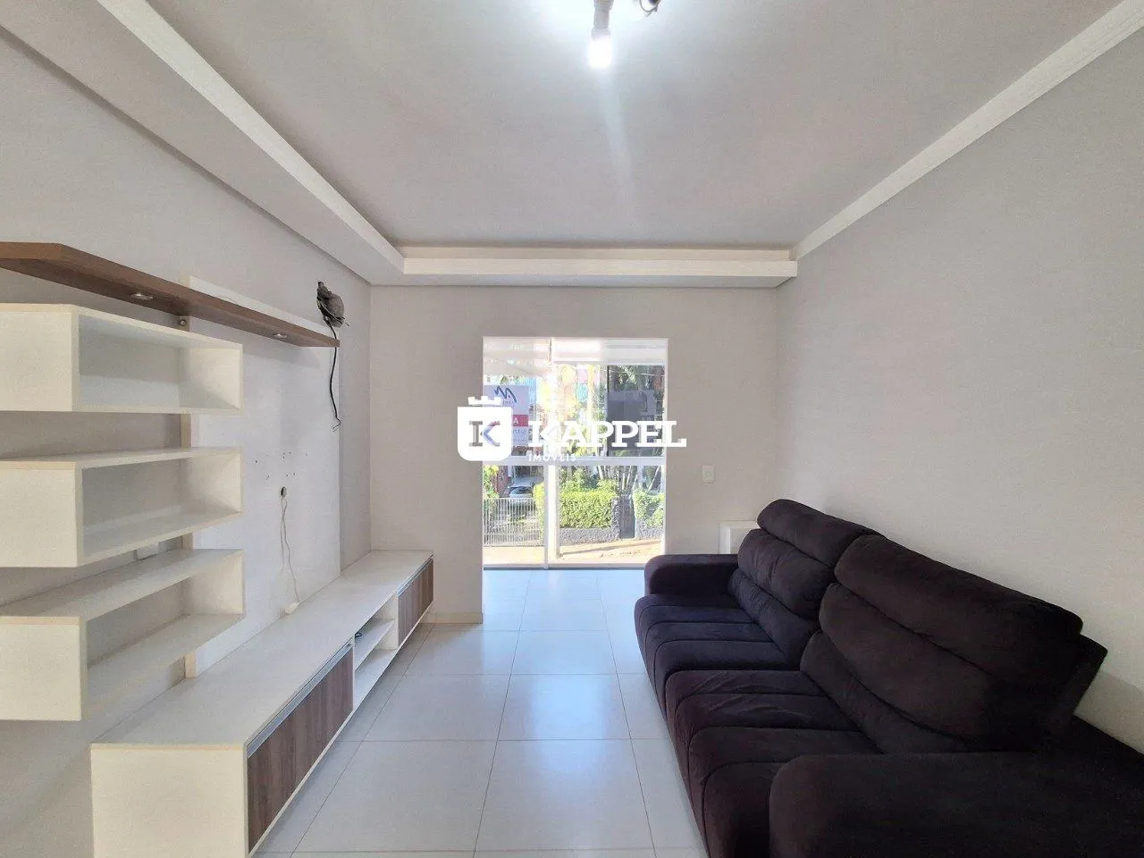 Uma sala de estar moderna com sofá e estantes brancas.