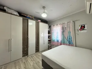 Quarto com armários brancos e piso de madeira clara.