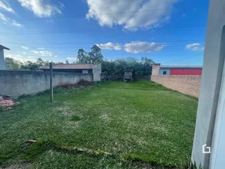 Vista externa de um quintal gramado com muro de vedação.