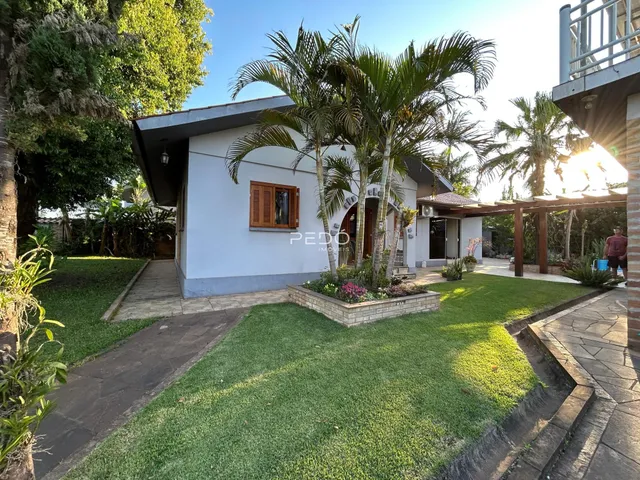Fachada de uma residência com jardim e palmeiras em Lajeado, Brasil.