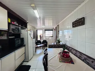 Interior de uma sala de estar com revestimento de azulejo branco e móveis de madeira.