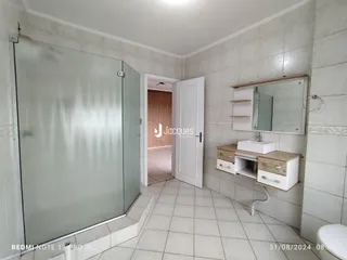 Interior de um banheiro com piso de cerâmica e box de vidro.