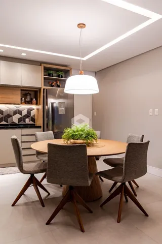 Mesa redonda de madeira com cadeiras em um ambiente interno.