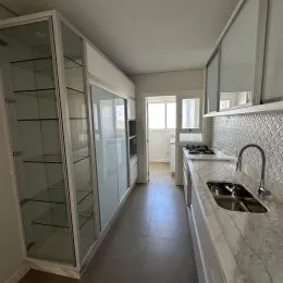 Uma foto de um corredor interno com paredes brancas e armários.
