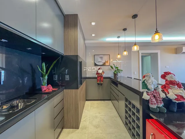 Vista da cozinha moderna com armários escuros e bancadas pretas.